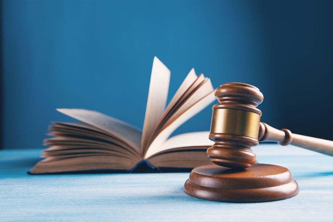 wooden gavel next to an open law book on a blue background